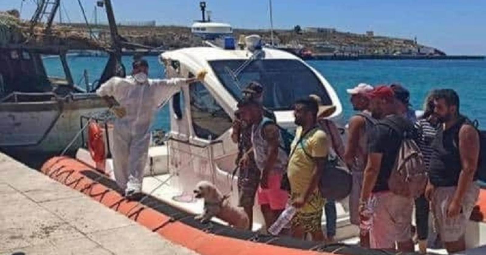 Lampedusa: lo sbarco di undici tunisini dal gommone dalla Guardia Costiera con bagagli, un barboncino al guinzaglio e cappelli di paglia